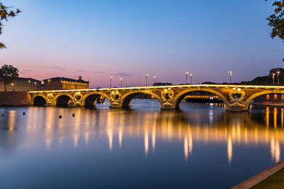 Bridge over river against clear sky during sunset