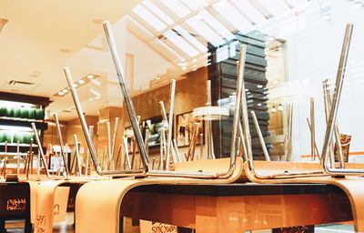 Upside down chairs on tables at restaurant seen from glass