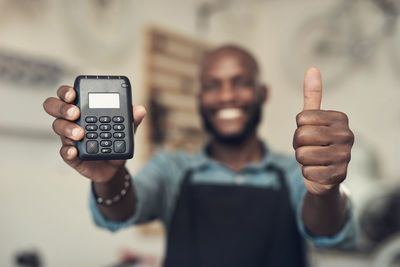 Happy man with calculator standing in cafe