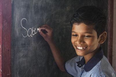 Close-up of boy writing on blackboard