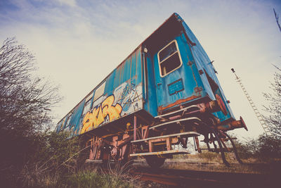 Low angle view of abandoned train on field against sky