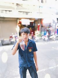 Portrait of boy standing on street in city