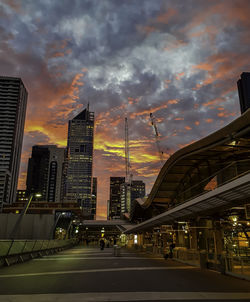 City street amidst buildings against sky during sunset