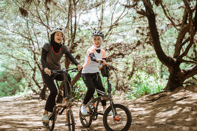 Female friends riding bicycle on road