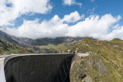 Scenic view of dam and mountains against cloudy sky