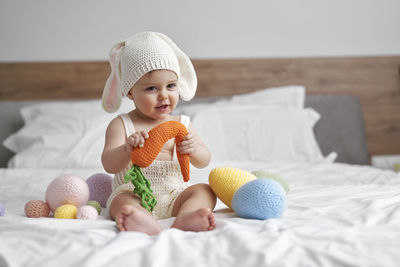 Smiling girl playing with toy sitting on bed at home