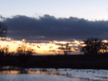 Scenic view of river against sky at sunset