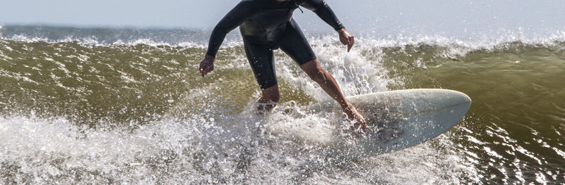 Front view of a man surfing and splashing in rough waves at gilgo beach on long island close up.