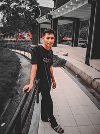 Portrait of smiling woman standing against railing