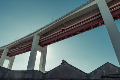 Low angle view of bridge and buildings against clear blue sky