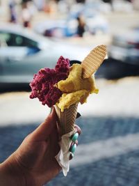 Cropped hand of person holding ice cream on footpath