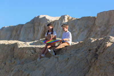 Children best friends sitting with a kite nature after school.