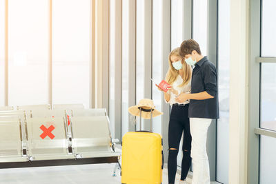 Portrait of young traveler in protective mask holds passport during affected by flight delay