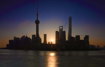 Modern buildings in city against sky during sunset