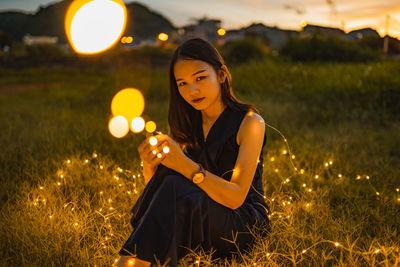 Woman holding illuminated lighting equipment on field