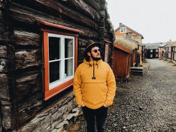 Portrait of young man standing against building during winter