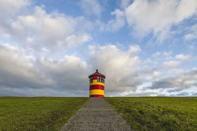 Lighthouse on field against sky