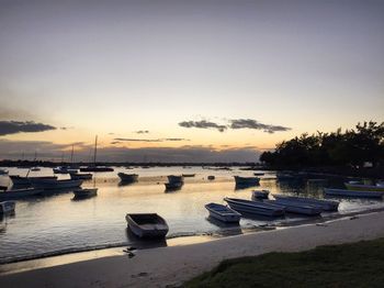 Boats moored in marina at sunset