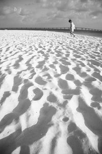 Shadow of woman walking on sand at beach