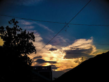 Low angle view of silhouette tree and building against sky