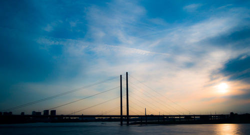 View of suspension bridge over river against cloudy sky