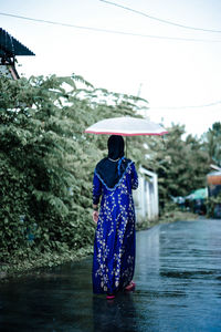 Rear view of woman with umbrella standing in water