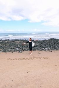 Woman standing on beach against sky