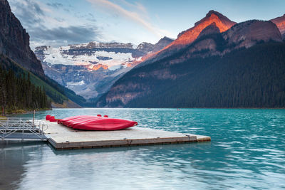 Red boats moored at harbor against mountains