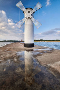 Lighthouse by sea against sky