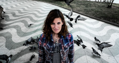 Portrait of smiling woman against pigeons on walkway