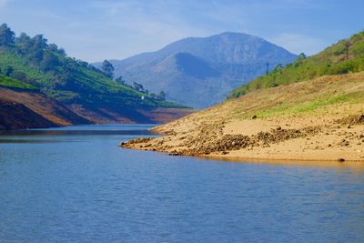 Scenic view of river by mountains against sky