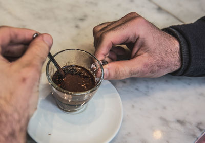 Cropped hand of man stirring coffee on table