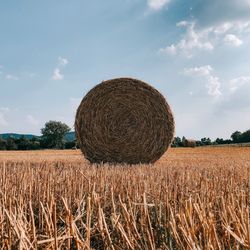 Hay bales on field against sky