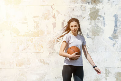 Portrait of a smiling young woman against wall