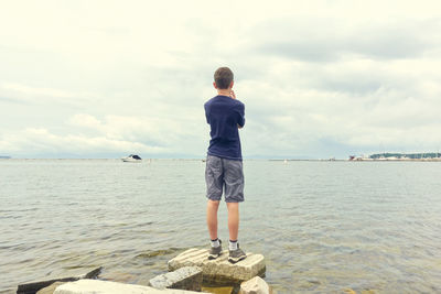 Rear view of man standing by sea against sky