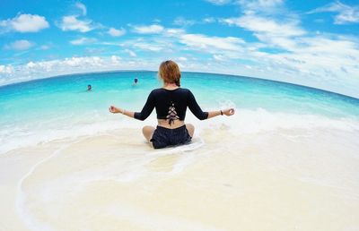 Woman sitting in sea against sky