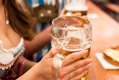 Midsection of woman having beer at restaurant