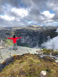 Rear view of man standing on mountain against sky