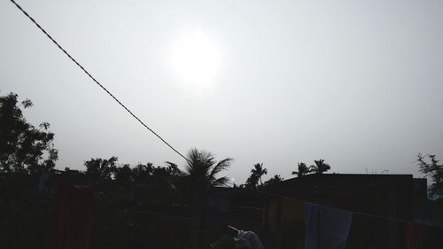 Low angle view of silhouette trees and buildings against sky