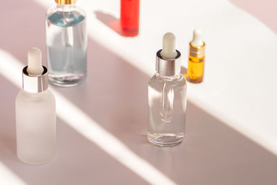 Different glass dropper bottles with face serum, natural oil and anti-age moisturizer in sunny room