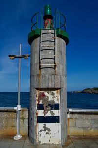 Lighthouse by sea against blue sky