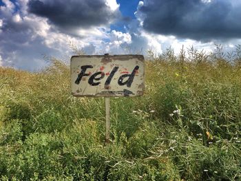 View of field against cloudy sky