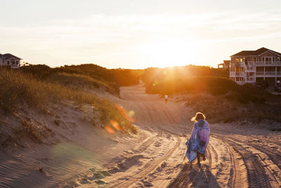 Rear view of girl wrapped in towel walking on sand