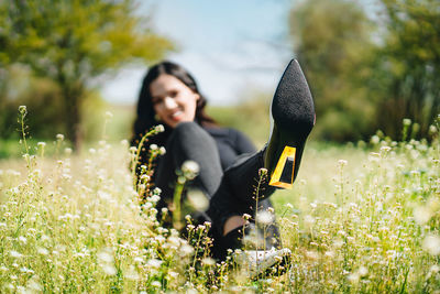 Woman with boots standing on field by flowering plants in summer