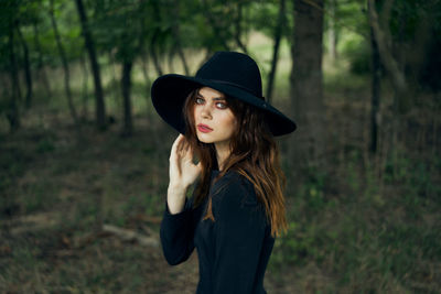 Portrait of young woman wearing hat standing on field