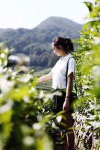 Woman standing by tree against sky
