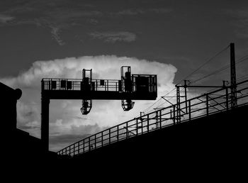 Low angle view of silhouette bridge against cloudy sky at dusk