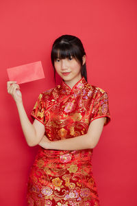 Portrait of a smiling young woman against red background