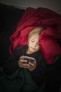 High angle view of girl using mobile phone while lying in tent