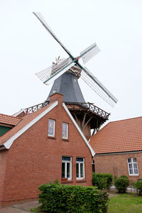 Low angle view of traditional windmill by house against clear sky